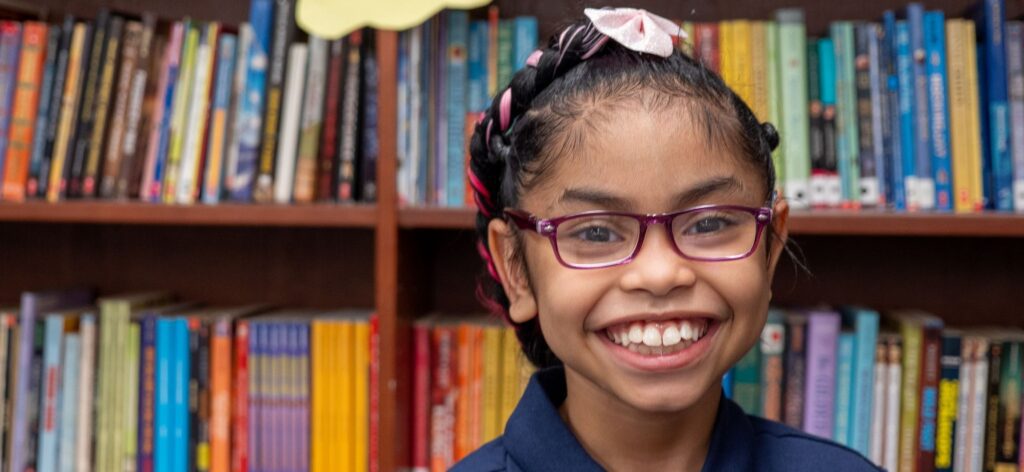 Smiling girl with glasses in library