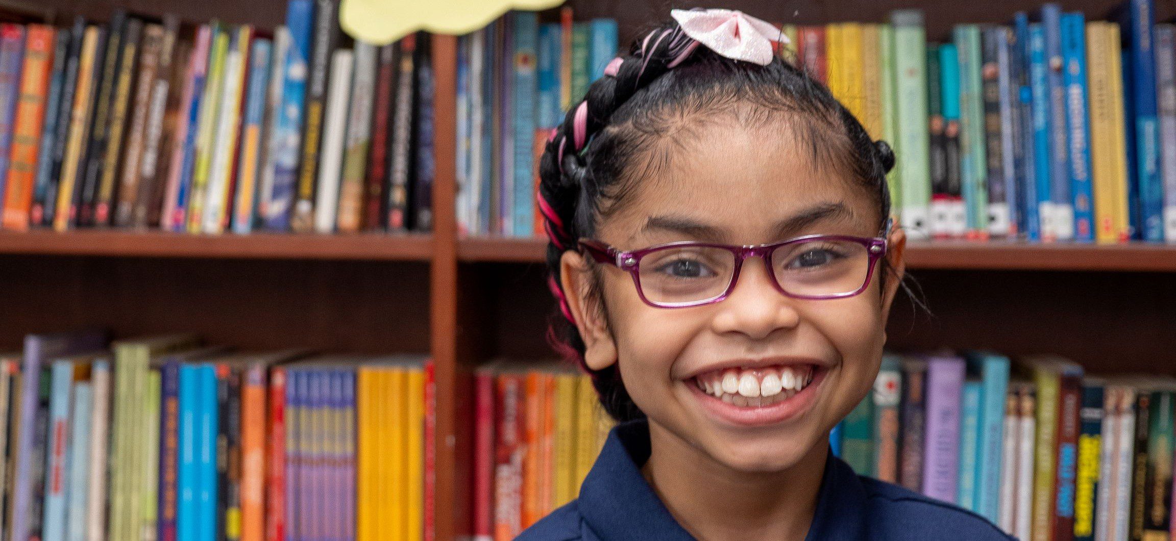 Smiling girl with glasses in library
