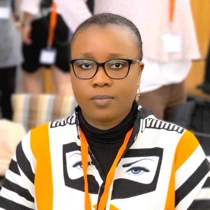 Woman in glasses and patterned shirt at event.