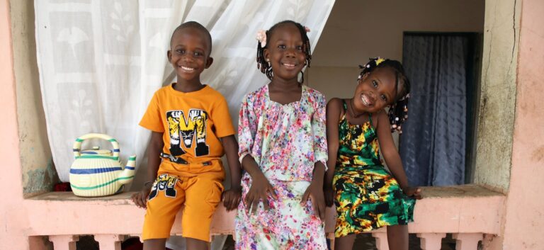 Smiling children sitting on porch ledge