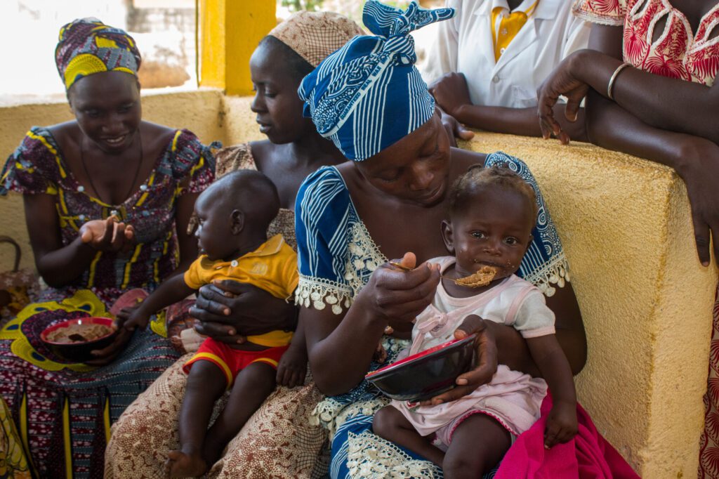 Mother feeding baby porridge with other women