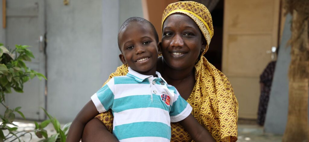 Mother holding smiling boy outside home
