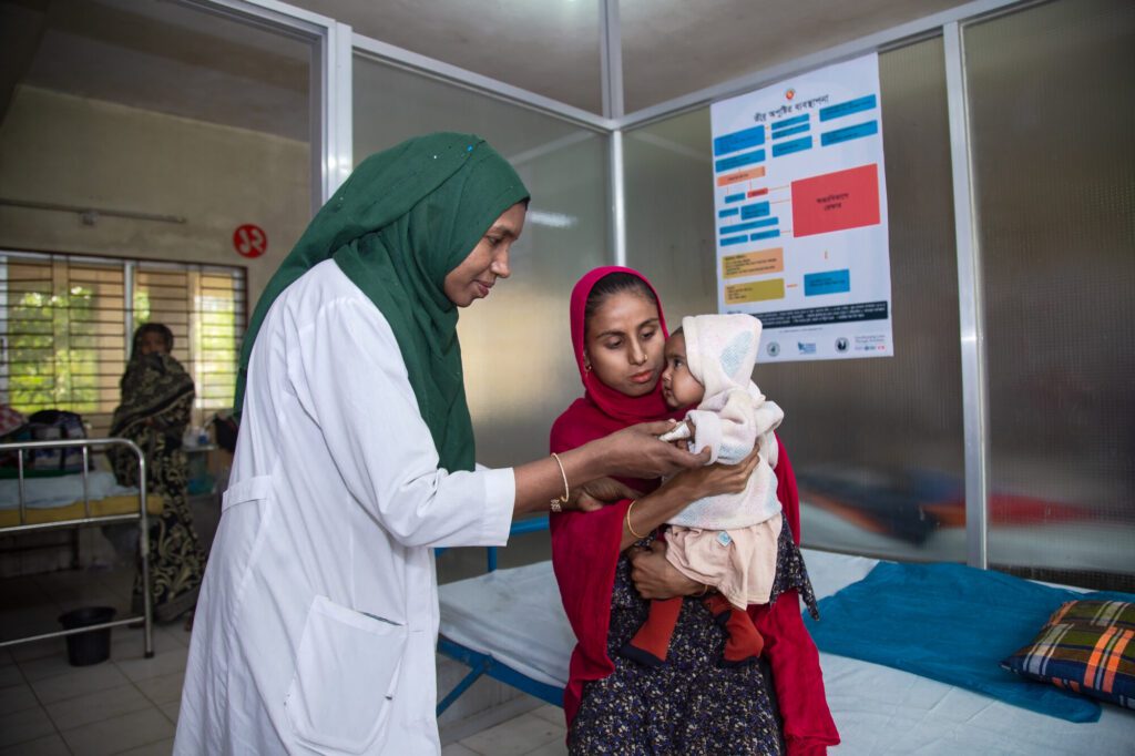 Doctor examining baby held by mother