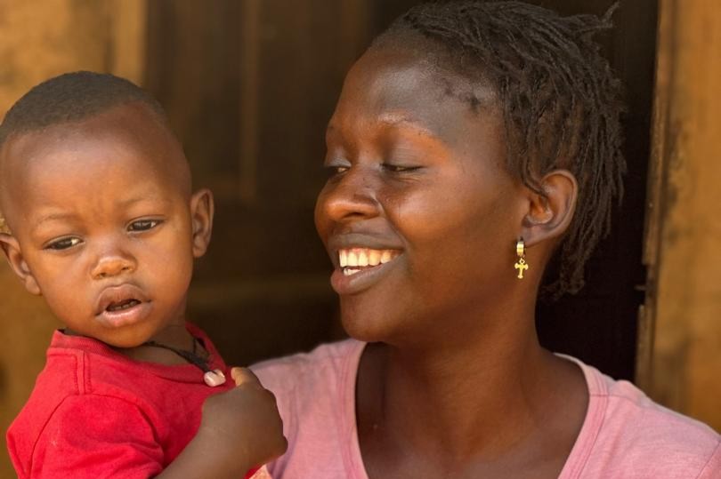 Woman smiling holding toddler in red shirt