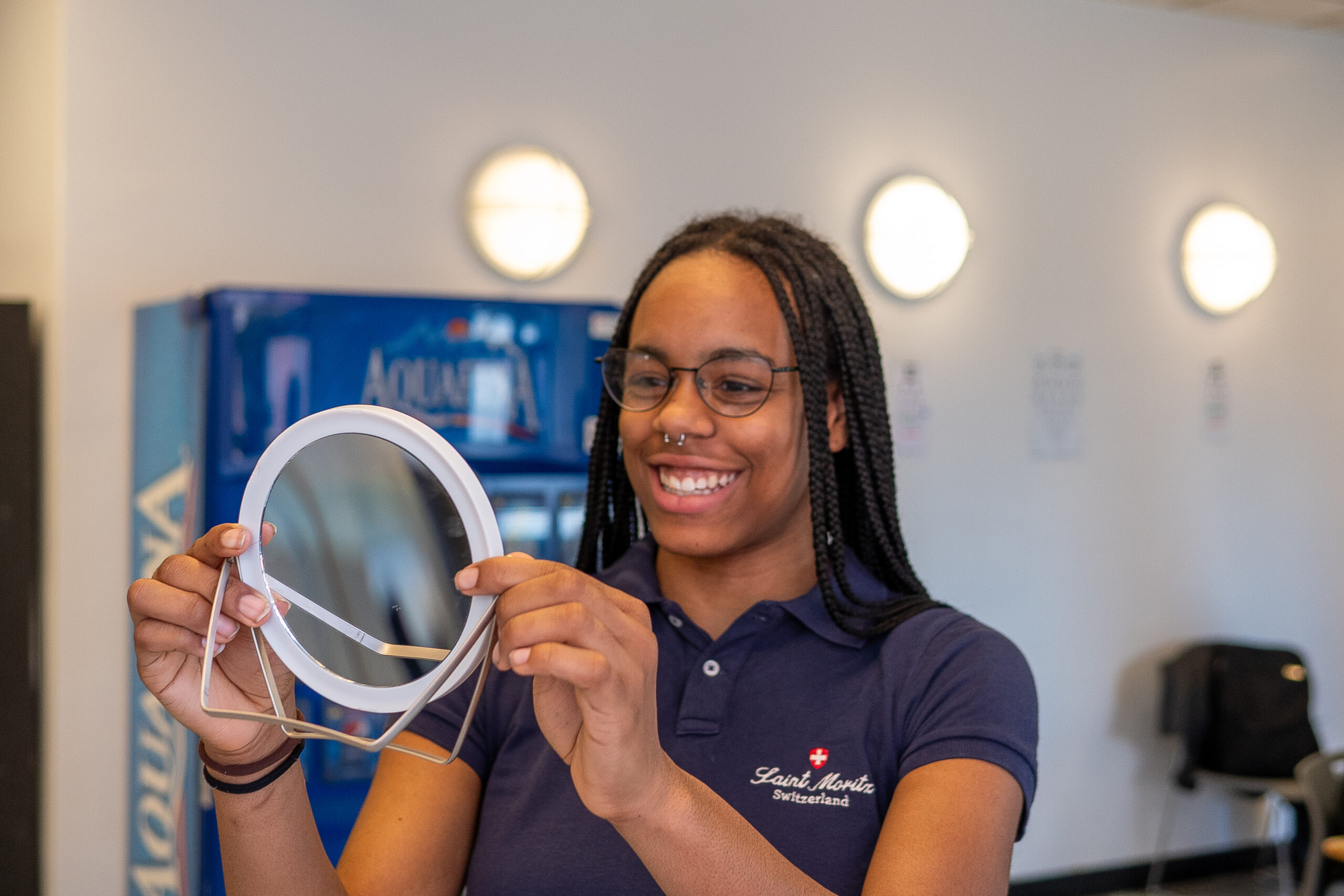 Woman holding round mirror smiling indoors