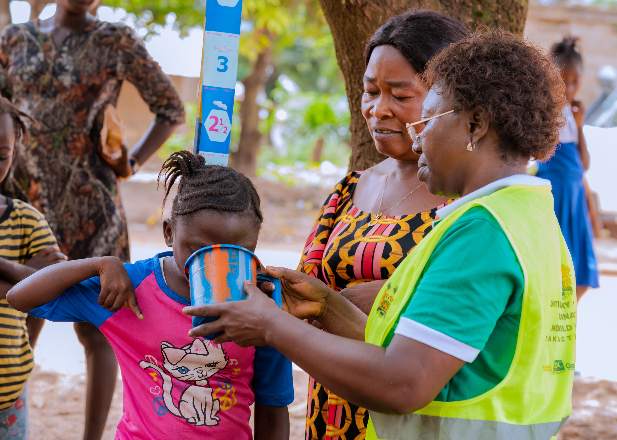 Woman measuring girl’s height with growth chart