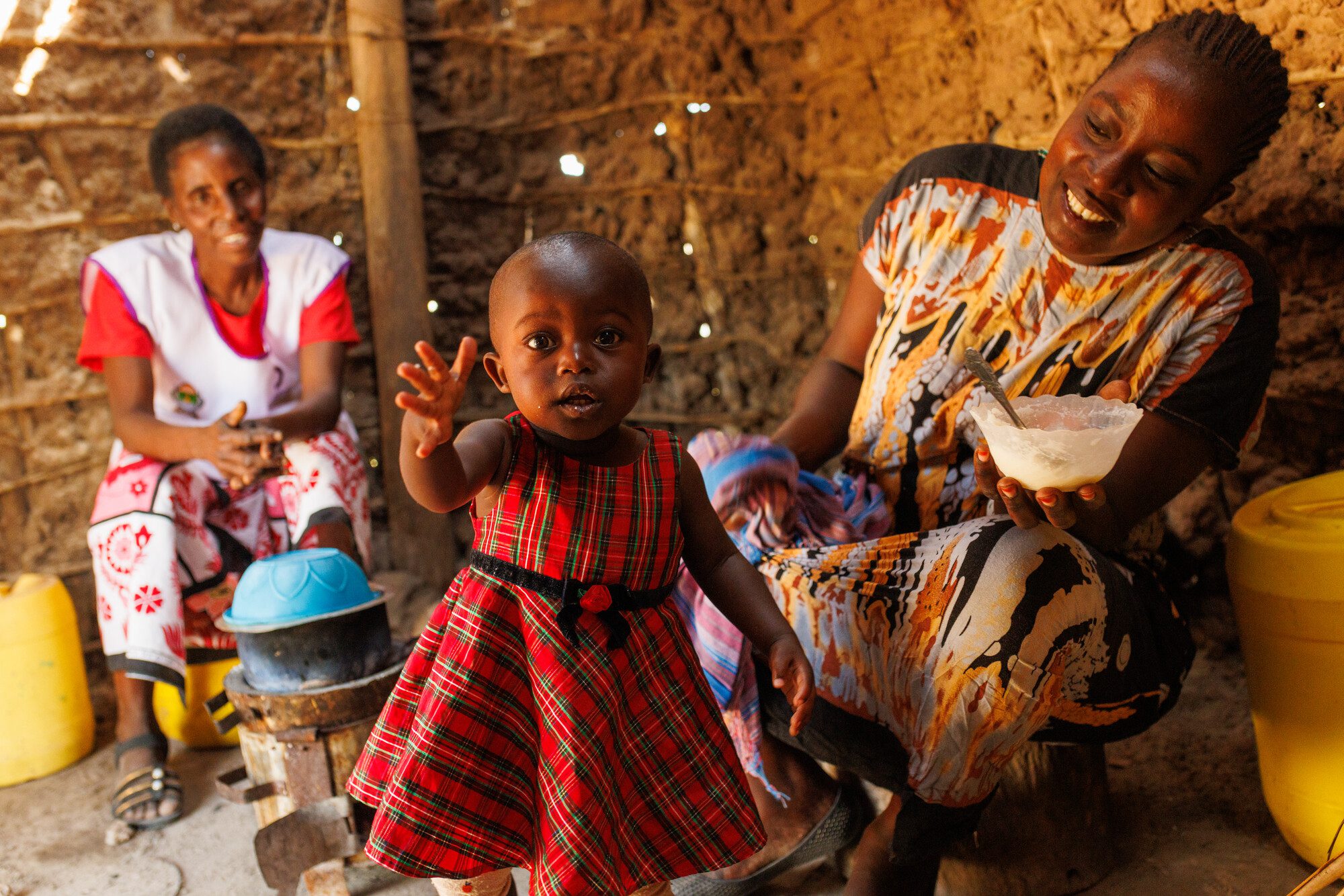 Baby girl in red dress reaching out indoors