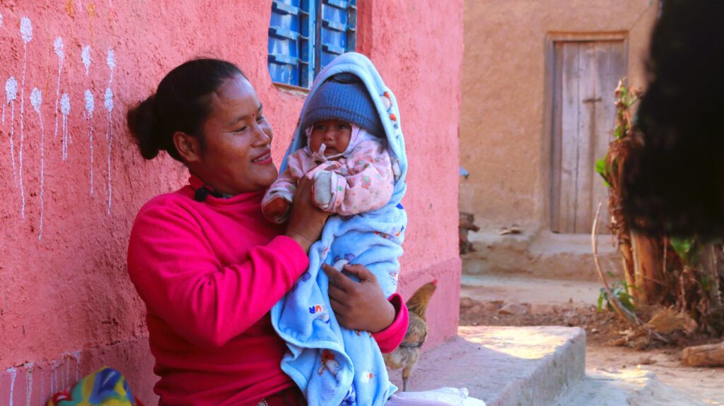 Woman holding baby wrapped in blue blanket
