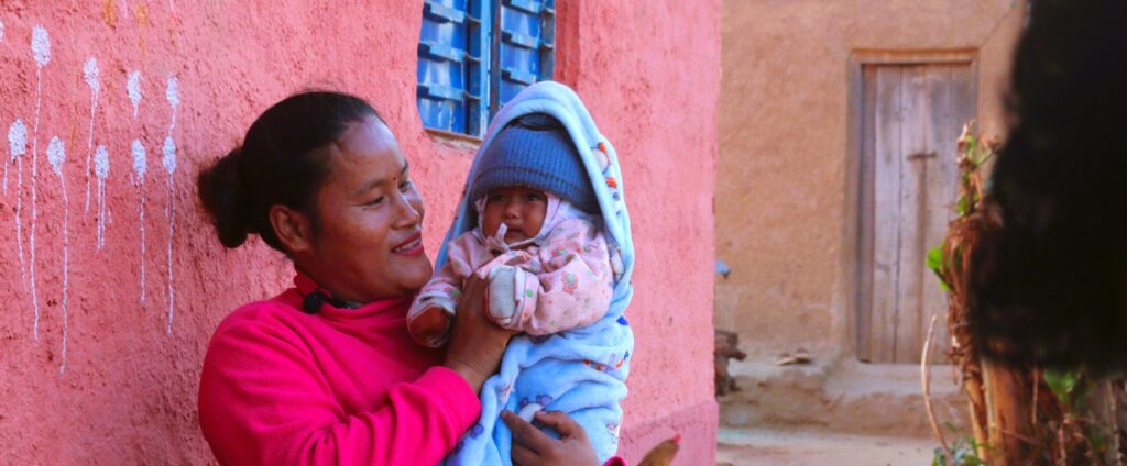 Woman holding baby wrapped in blue blanket