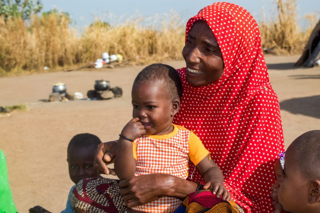 Woman in red hijab holding baby outdoors