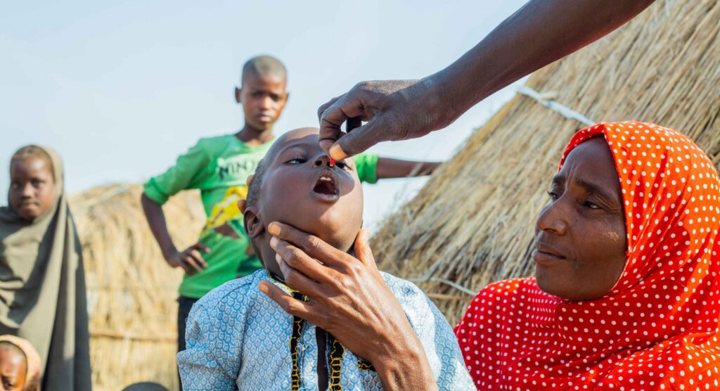 Child getting oral vitamin A supplement outdoors