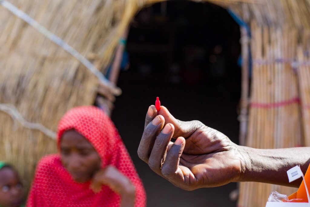 Hand holding red malaria test marker