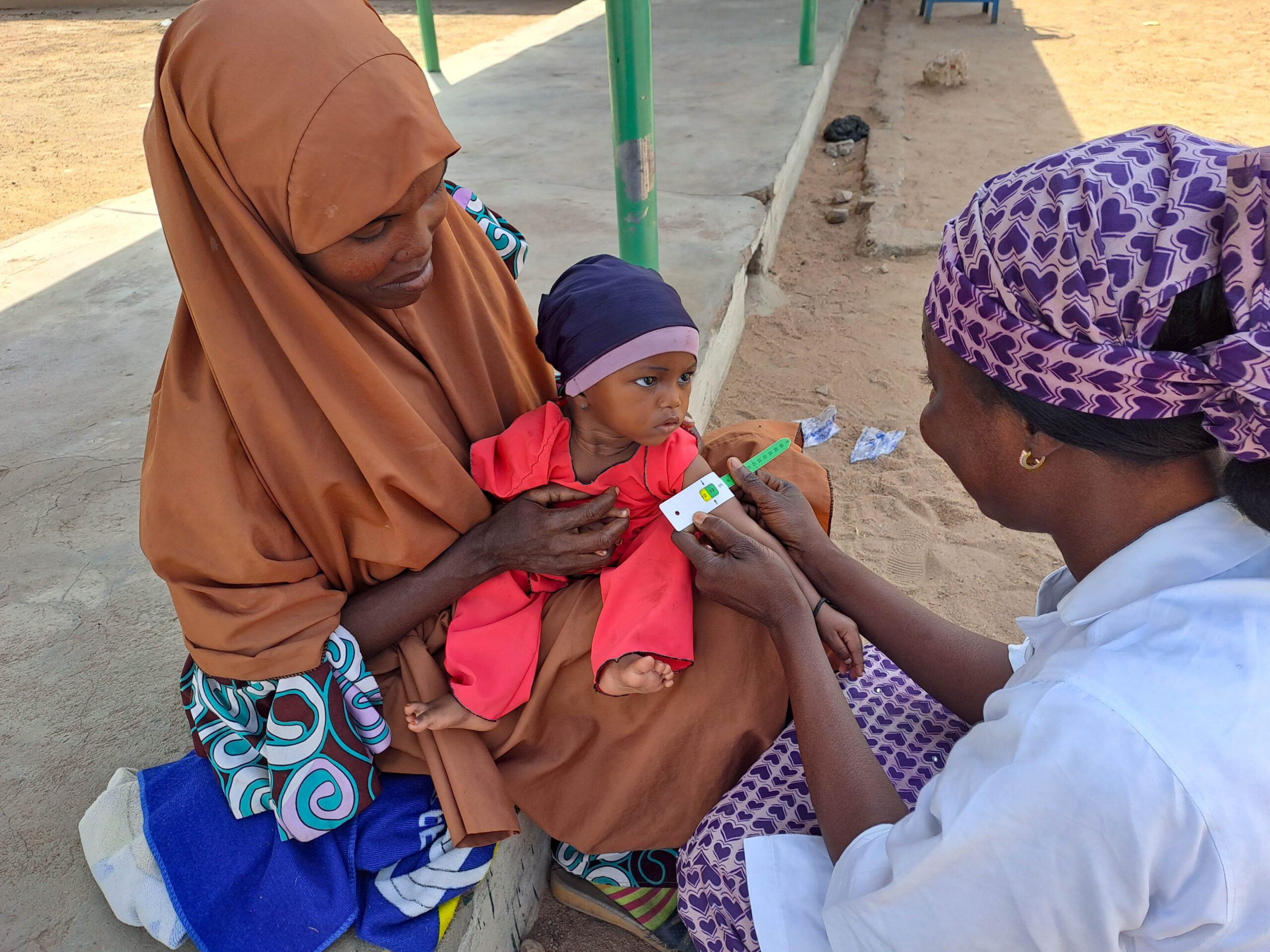 Health worker measuring baby arm circumference