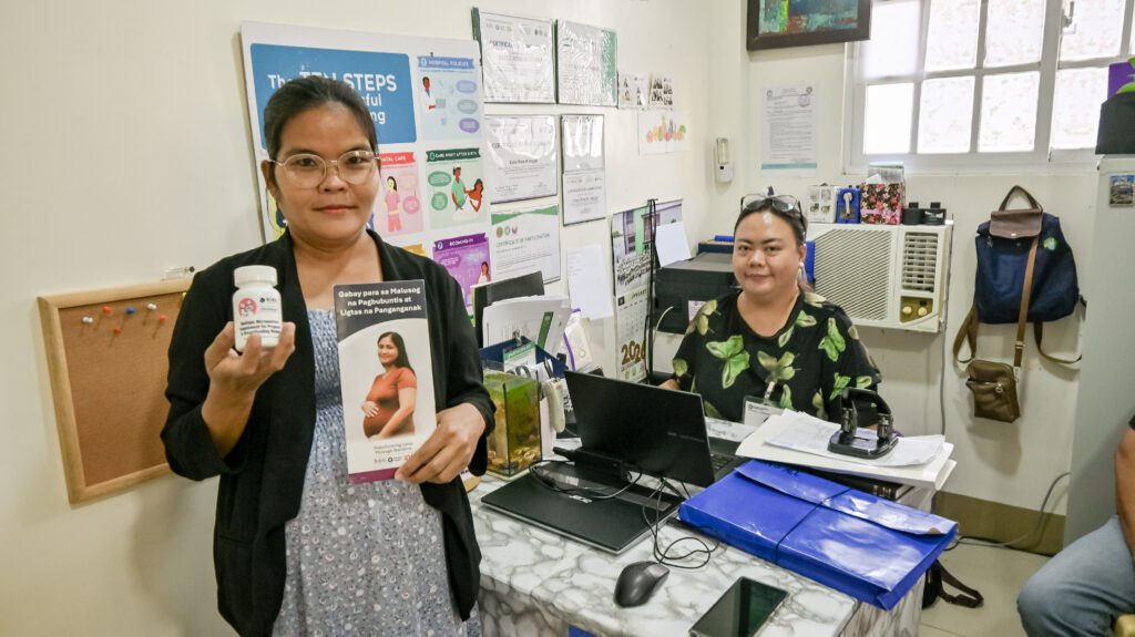 Pregnant woman holding supplement and brochure
