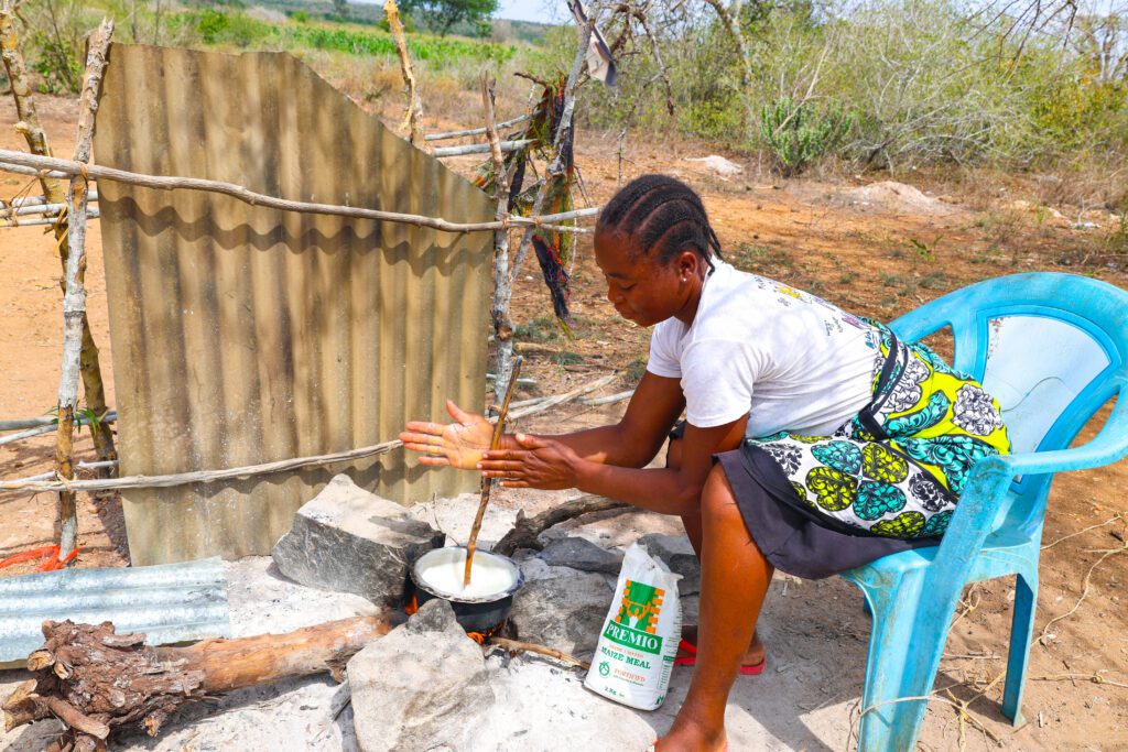 Woman cooking maize meal porridge outdoors