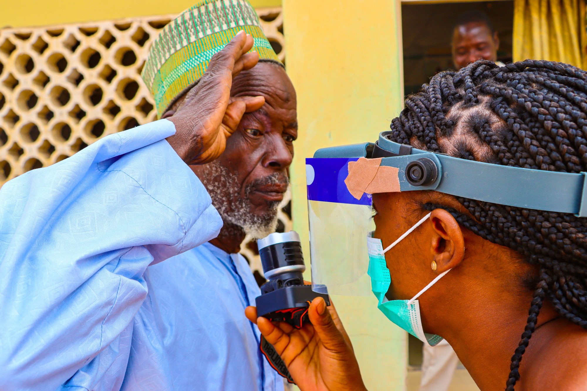 Elderly man receiving eye exam with device