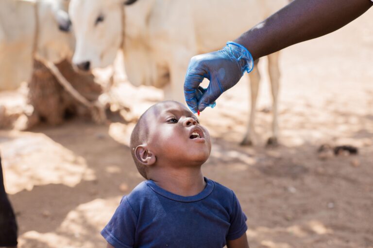 Child receiving oral vaccine drop outdoors