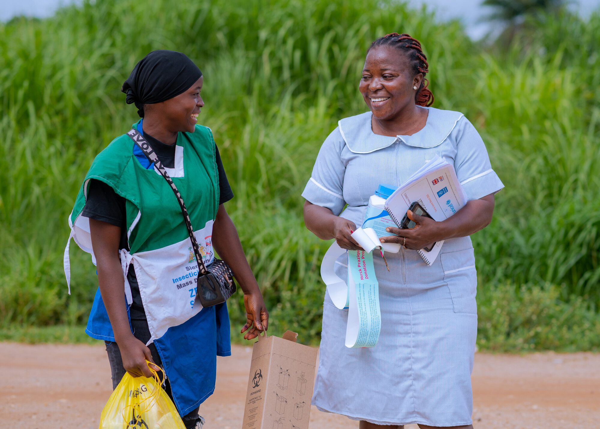 Women holding medical supplies smiling outdoors