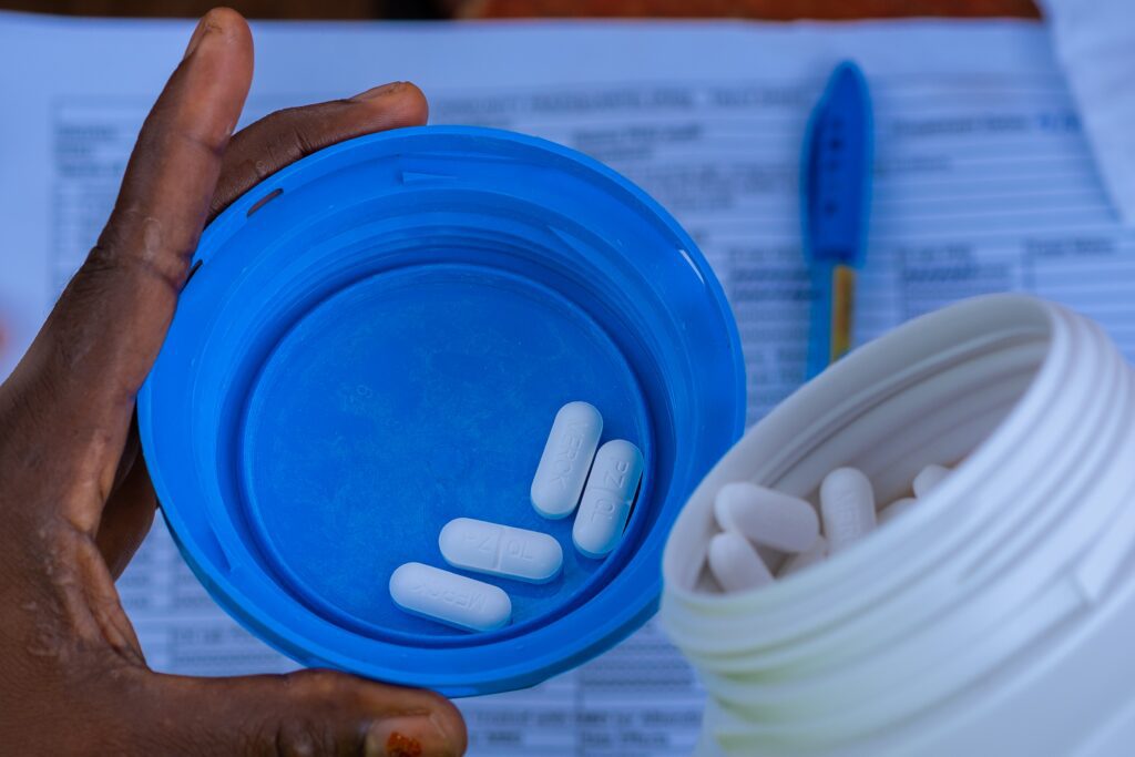Hand holding blue cap with white pills