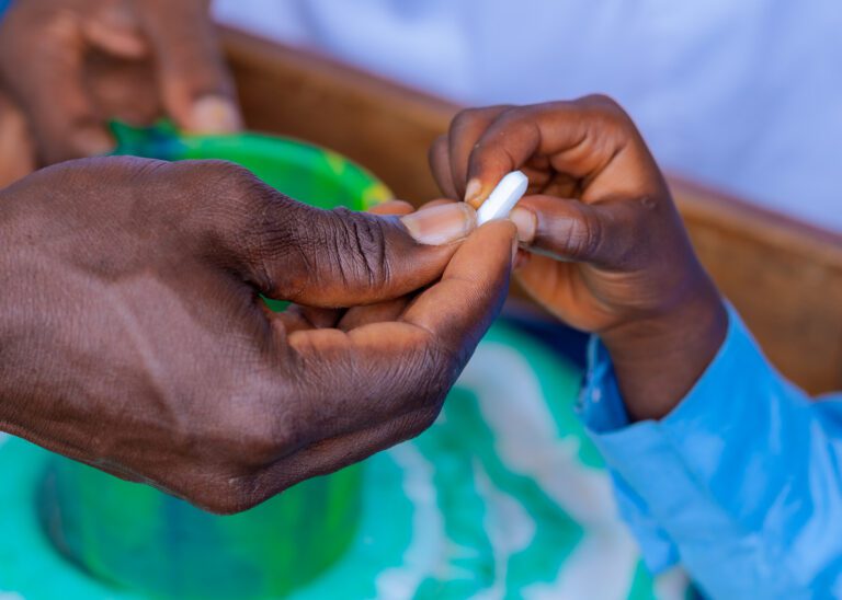 Child giving white pill to adult hand