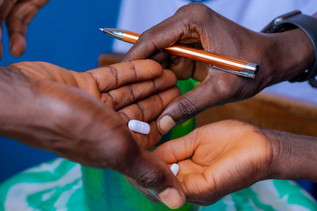 Hands receiving white pill from healthcare worker