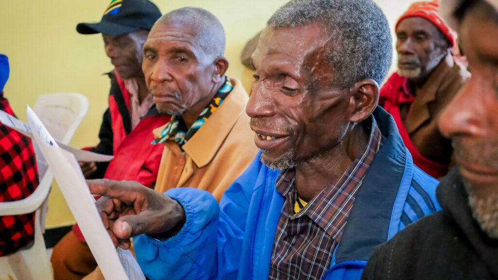Elderly men reading papers in group