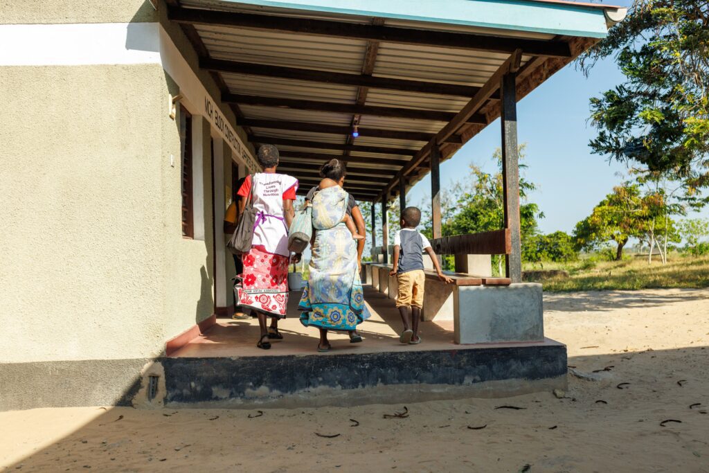 Health worker walking with mother and children outdoors