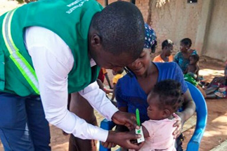 Health worker measuring baby’s arm circumference