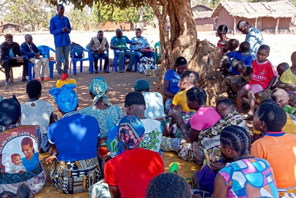 Community health outreach meeting under tree