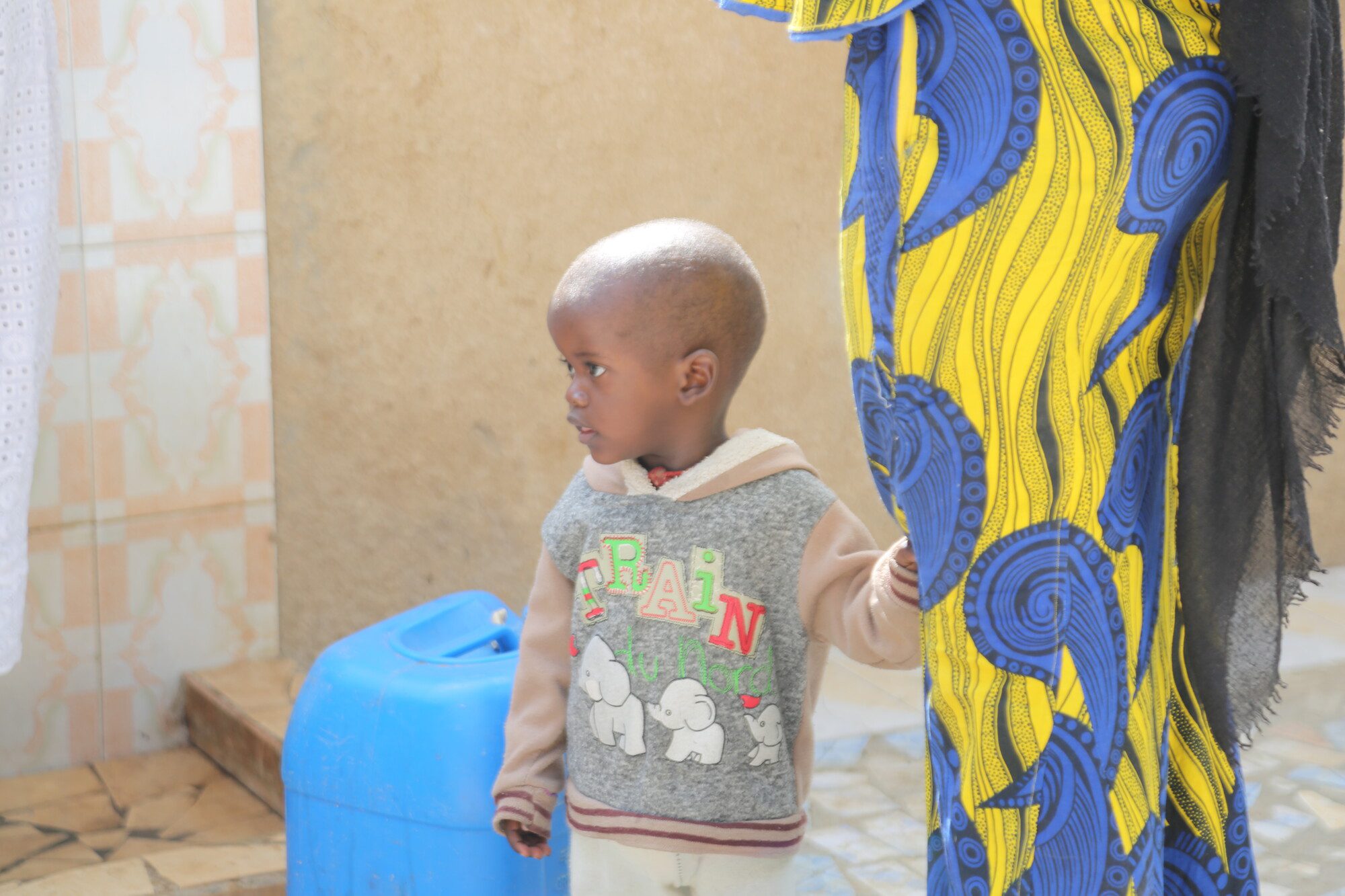 Child holding colorful fabric indoors