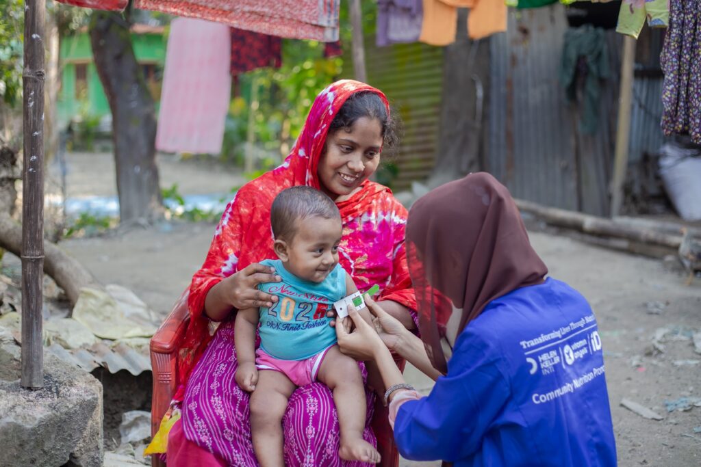 Health worker measuring baby arm circumference outdoors