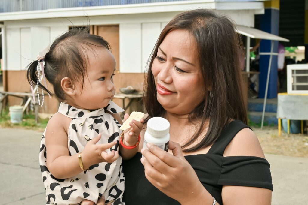 Mother feeding baby girl milk and biscuit