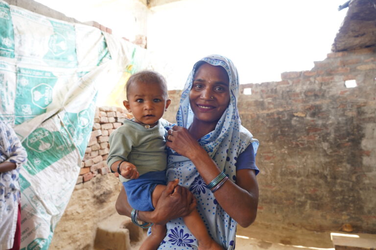 Indian woman holding baby in rustic home