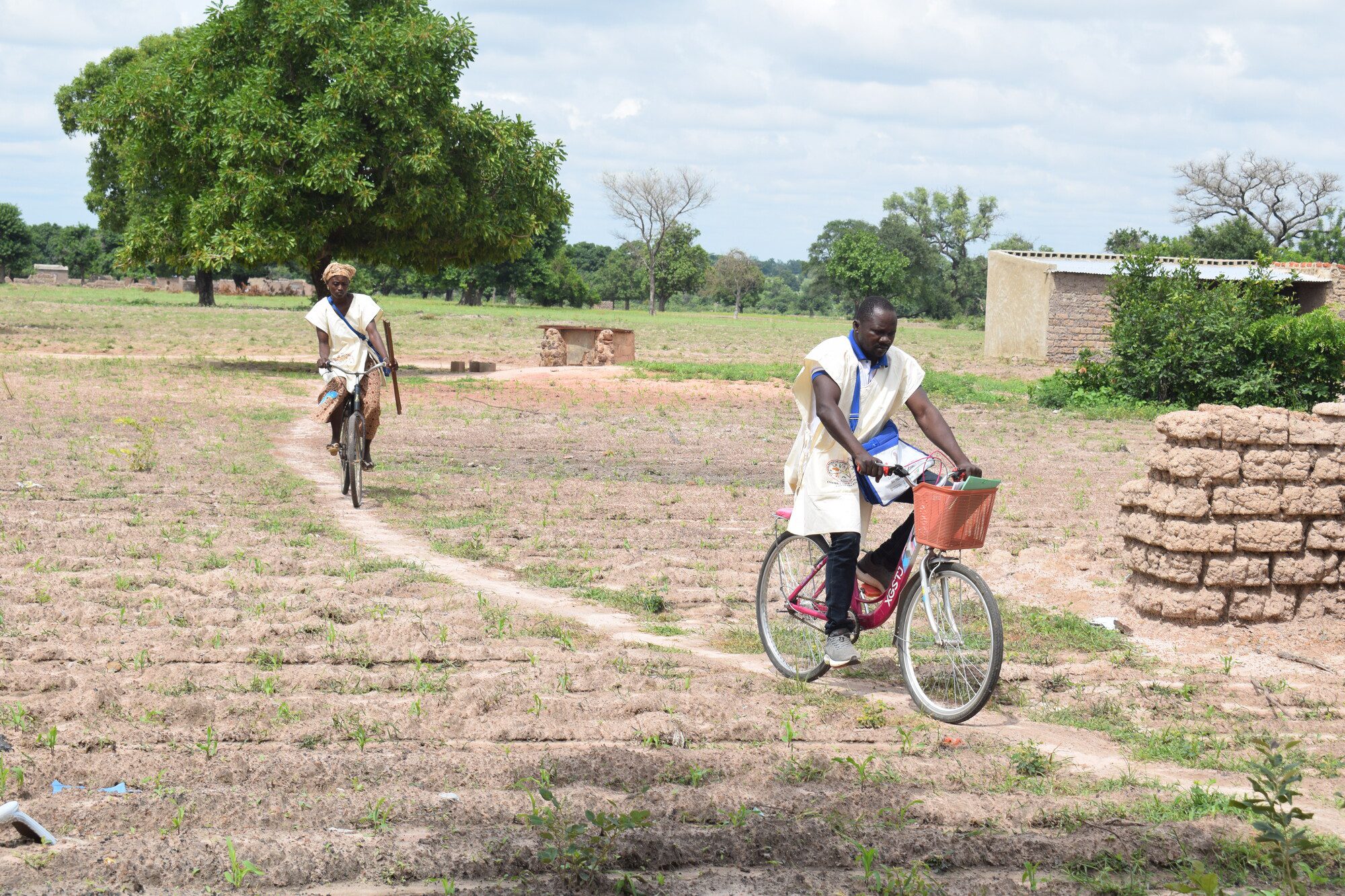 Health workers cycling on rural dirt path