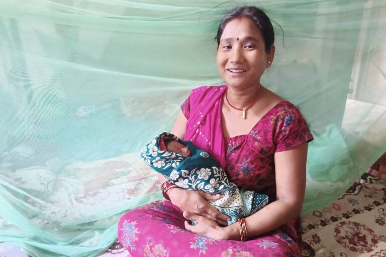 Woman holding baby under mosquito net