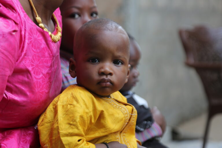 Child in yellow shirt is held by his mother