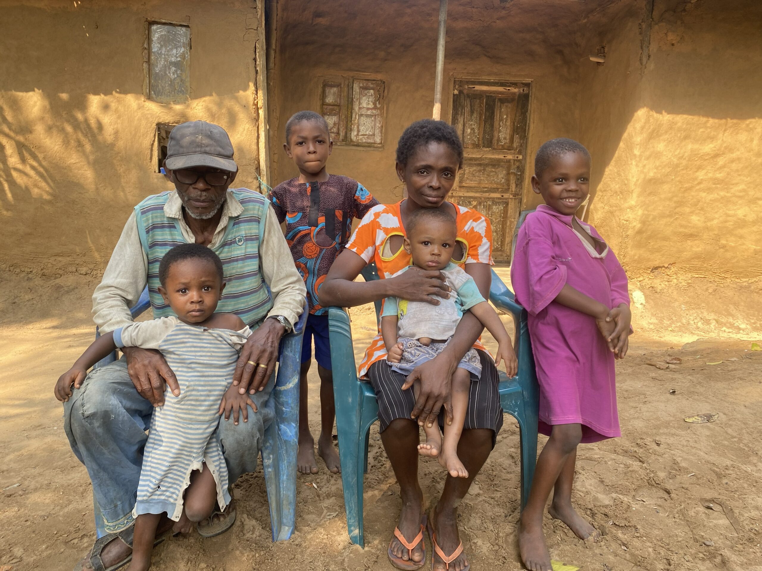 Mother holds her young child, surrounded by her husband and three other children