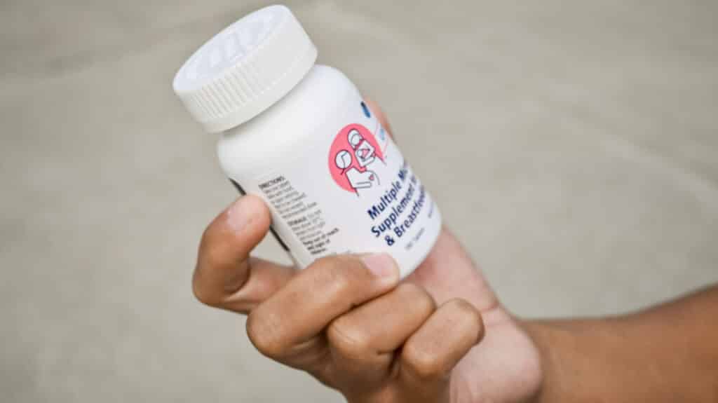 Hand holding bottle of multiple micronutrient supplements