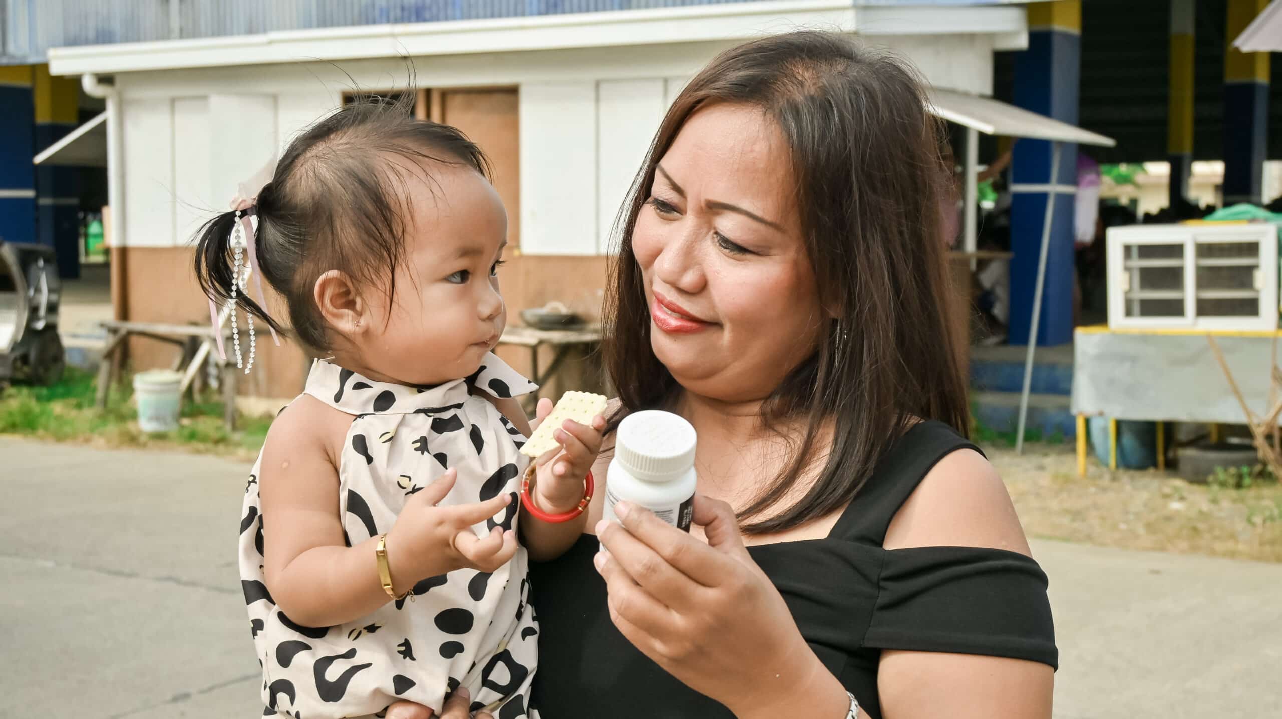 Mother holds her young daughter, along with a bottle of medication.