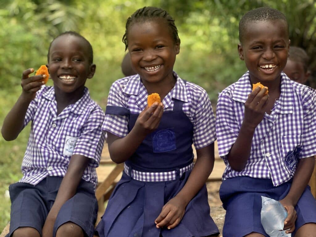 Three young children enjoy orange-flesh sweet potatoes