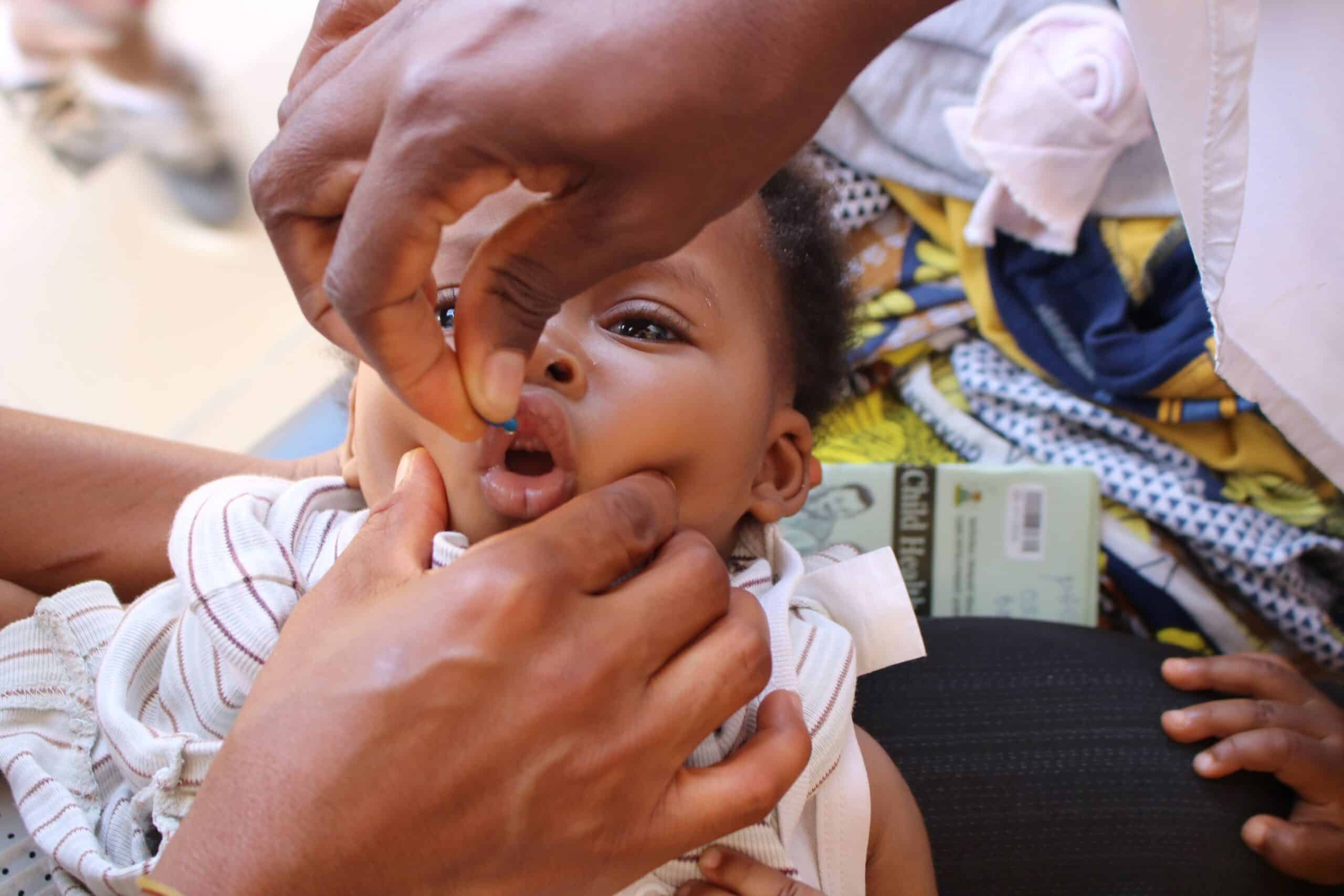 A health worker administering a Vitamin A capsule drop to a child in Nigeria.